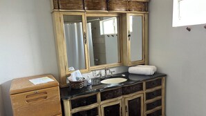 Een badkamer met een houten wastafelmeubel, een wastafel, een spiegel en een douchegordijn.