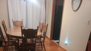 Et spiseområde med et træbord og stole, en rød sofa og en vægmonteret lampe.