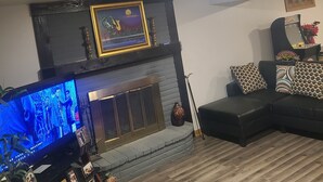 En stue med pejs, fjernsyn og sofa.