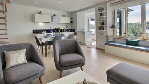 Een moderne woonkamer met grijze banken, een eethoek en een keuken.