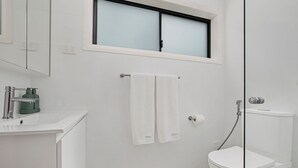 Une salle de bain avec des toilettes, un lavabo, un miroir et une fenêtre.