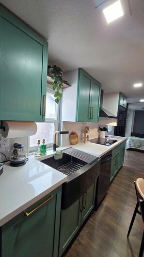 A kitchen with green cabinets, a black and white countertop, and a wooden floor. - Cozy Private Retreat (Phoenix)