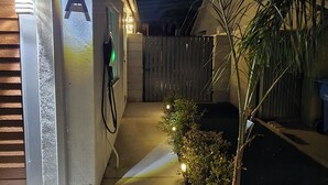Un garage residenziale con la lettera 'A' illuminata sulla porta, un vialetto che conduce al garage e un piccolo albero decorato con luci.
