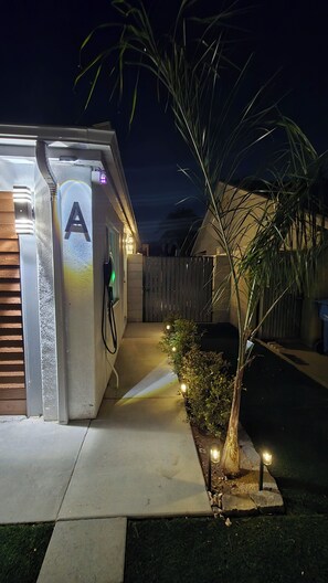 A residential garage with a letter 'A' illuminated on the door, a driveway leading to the garage, and a small tree with lights. - Cozy Private Retreat (Phoenix)