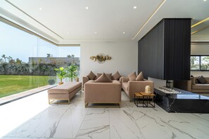 Ein modernes Wohnzimmer mit einer Eckcouch, einem Couchtisch und einem großen Fenster mit Blick auf einen Garten.
