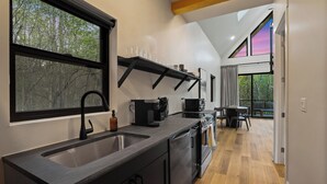 A modern kitchen with a large window, a built-in oven, and a dining area with a view. - Spiral Loft · Hot Tub · Spa Bath | Lux Sleeps 4 (McArthur)