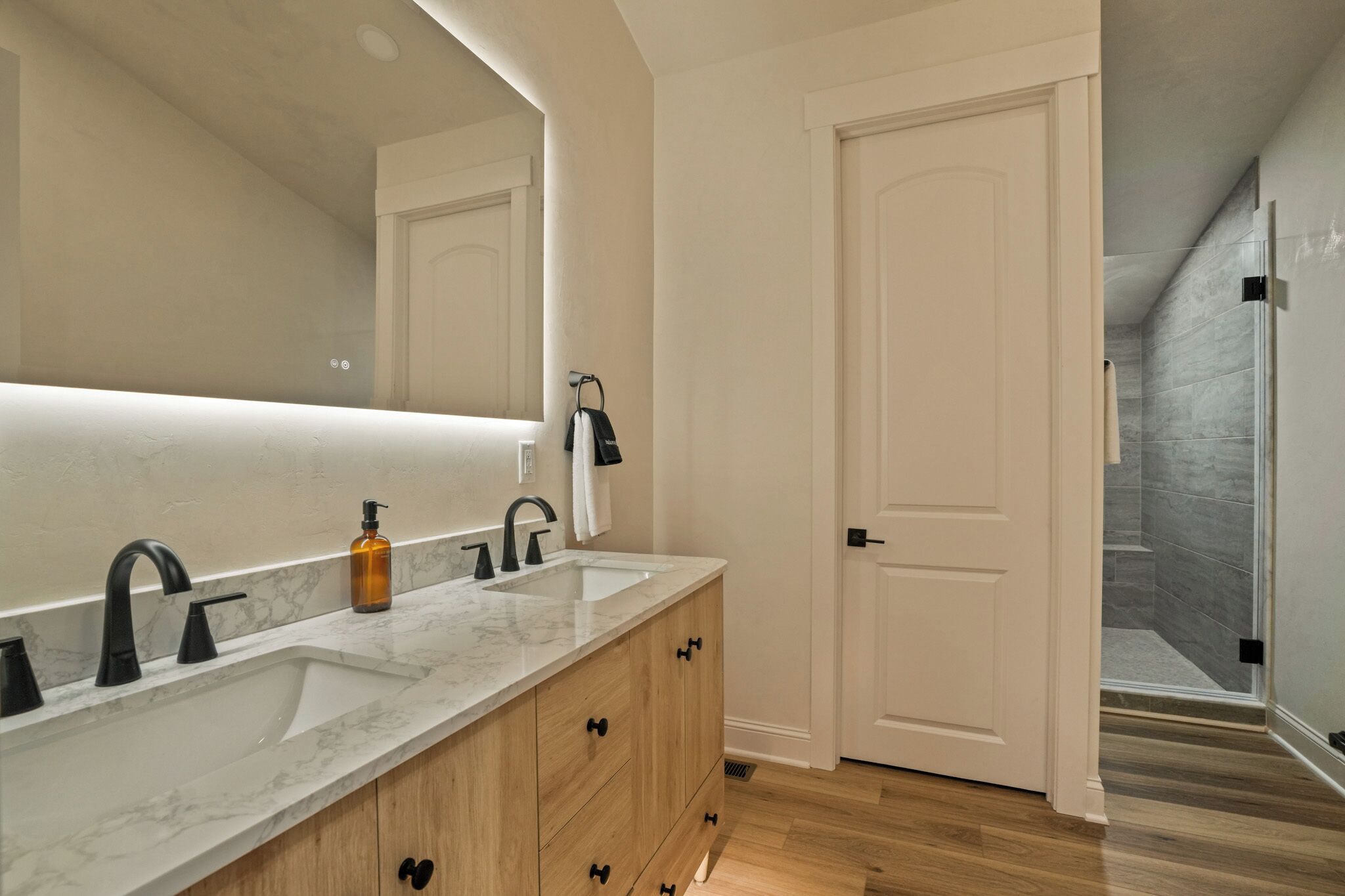 Une salle de bain avec un double lavabo, un grand miroir et des meubles en bois.