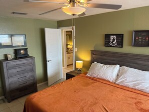 Une chambre d’hôtel équipée d’un lit, d’une commode, d’un ventilateur de plafond et d’une porte donnant accès à une salle de bain.