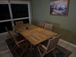 Un coin repas avec une table et des chaises en bois, une porte vitrée et un tableau encadré au mur.