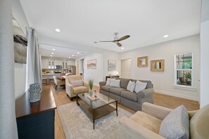 Ein modernes Wohnzimmer mit einem Glastisch, Sofas und einem Deckenventilator.