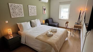 A neatly arranged bedroom with a bed, bedside table, lamp, and a small desk with a chair.