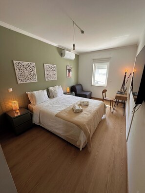 A neatly arranged bedroom with a bed, bedside table, lamp, and a small desk with a chair. - Santa Maresia Apartment [Santa Luzia] (Santa Luzia)