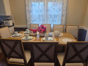 A dining table set with plates, cups, a vase of flowers, and a decorative shell.
