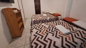 Habitación de hotel con dos camas, televisión, banco de madera y una puerta.