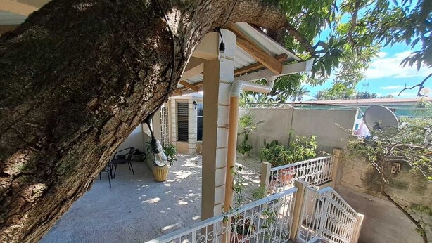 Un balcón con vistas a un jardín, una antena parabólica y una puerta de madera.