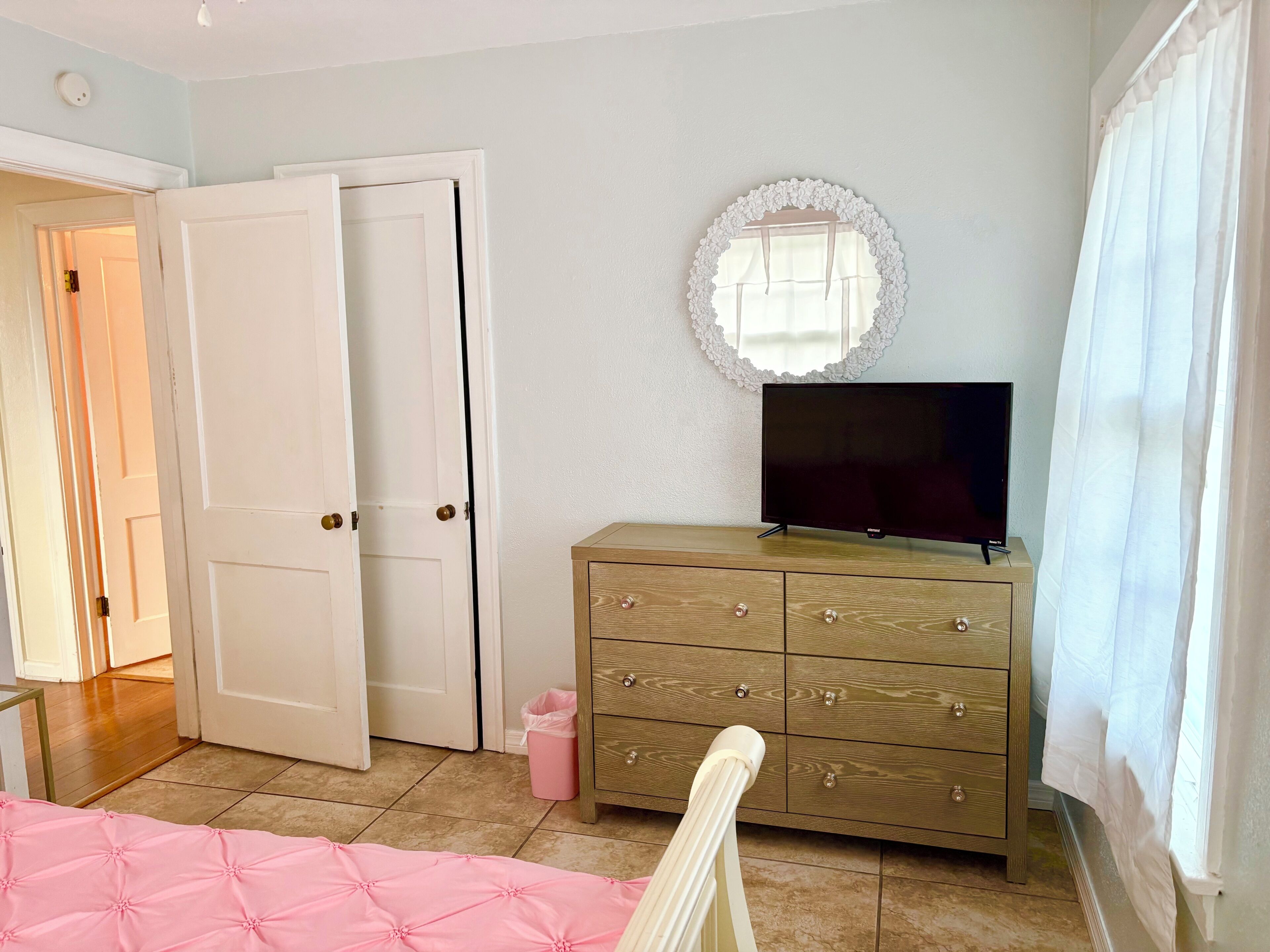 Un dormitorio con cama, cómoda, televisor y puerta.