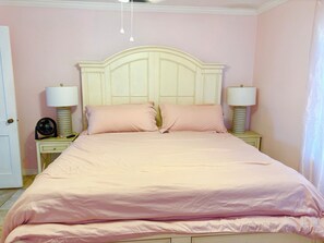 Ein Schlafzimmer mit einem Bett, zwei Nachttischen mit Lampen und einer Tür.