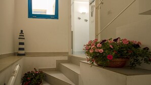A staircase with a potted plant of pink flowers, a lighthouse decoration, and a window with a blue frame. - Blue House Relax -Cozy family apartment 3 minutes from the sea (Marina di Ragusa)