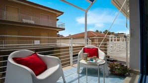 A balcony with two white chairs, a small table with a cup and saucer, and a flower pot. - Blue House Relax -Cozy family apartment 3 minutes from the sea (Marina di Ragusa)