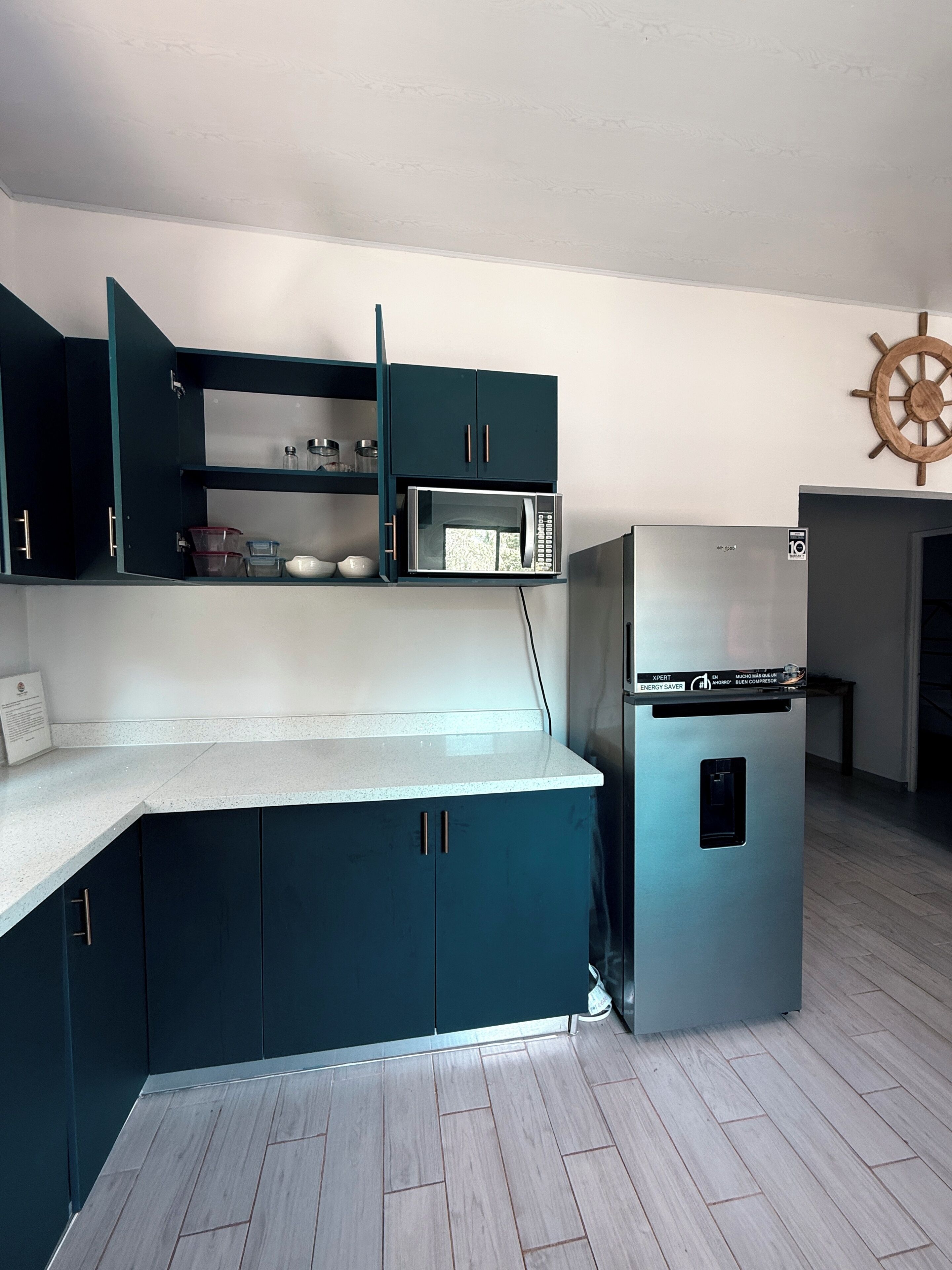 Una cocina compacta con armarios color turquesa, un microondas y un refrigerador.