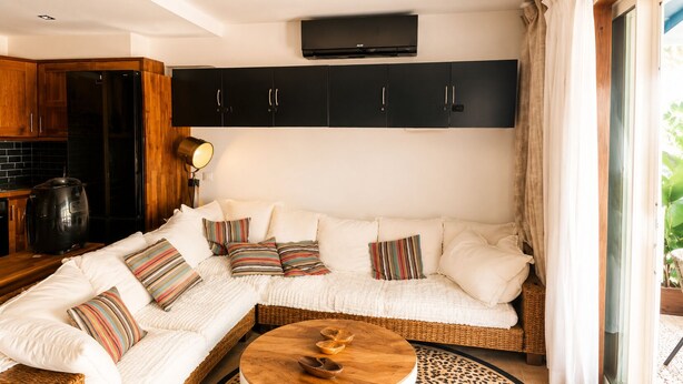 Una sala moderna con un sofá seccional, una mesa de centro y una zona de cocina con estufa y armarios.