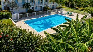 Un gran complejo turístico con piscina, varios balcones y exuberante vegetación.
