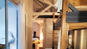 Ein Korridor mit Stockbetten, einer Glastür und einem Bett im Hintergrund.