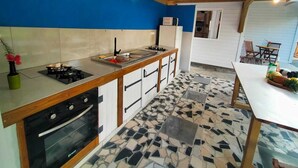 Eine Küche mit Herd, Spüle und Backofen, ein Essbereich mit Tisch und Stühlen sowie ein fußbodenbelesenes Parkett.