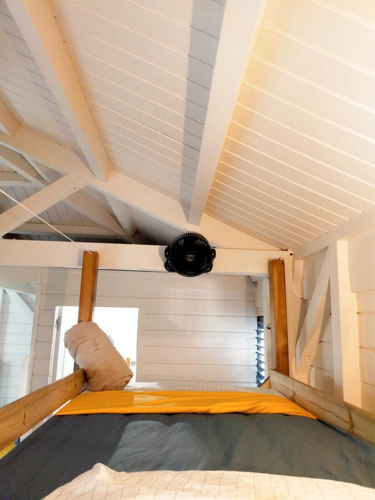 A bunk bed with a headboard, a ceiling fan, and a window.