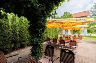 An outdoor patio with tables and chairs, yellow umbrellas, and a building in the background.