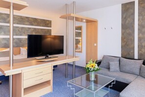 En moderne stue med fjernsyn, sofa, sofabord og en dekorativ vase.