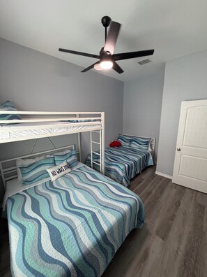 Um quarto com beliches, um ventilador de teto e uma porta.