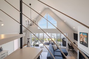 A modern loft-style room with a large skylight, a dining area, and a cozy seating space.
