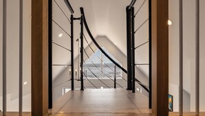 Un interior moderno con una escalera que lleva a un balcón con vistas al mar.