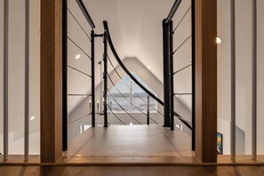 Ein modernes Interieur mit einer Treppe, die zu einem Balkon mit Meerblick führt.