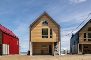 A two-story building with a wooden facade, a red building to the left, and a blue building to the right.