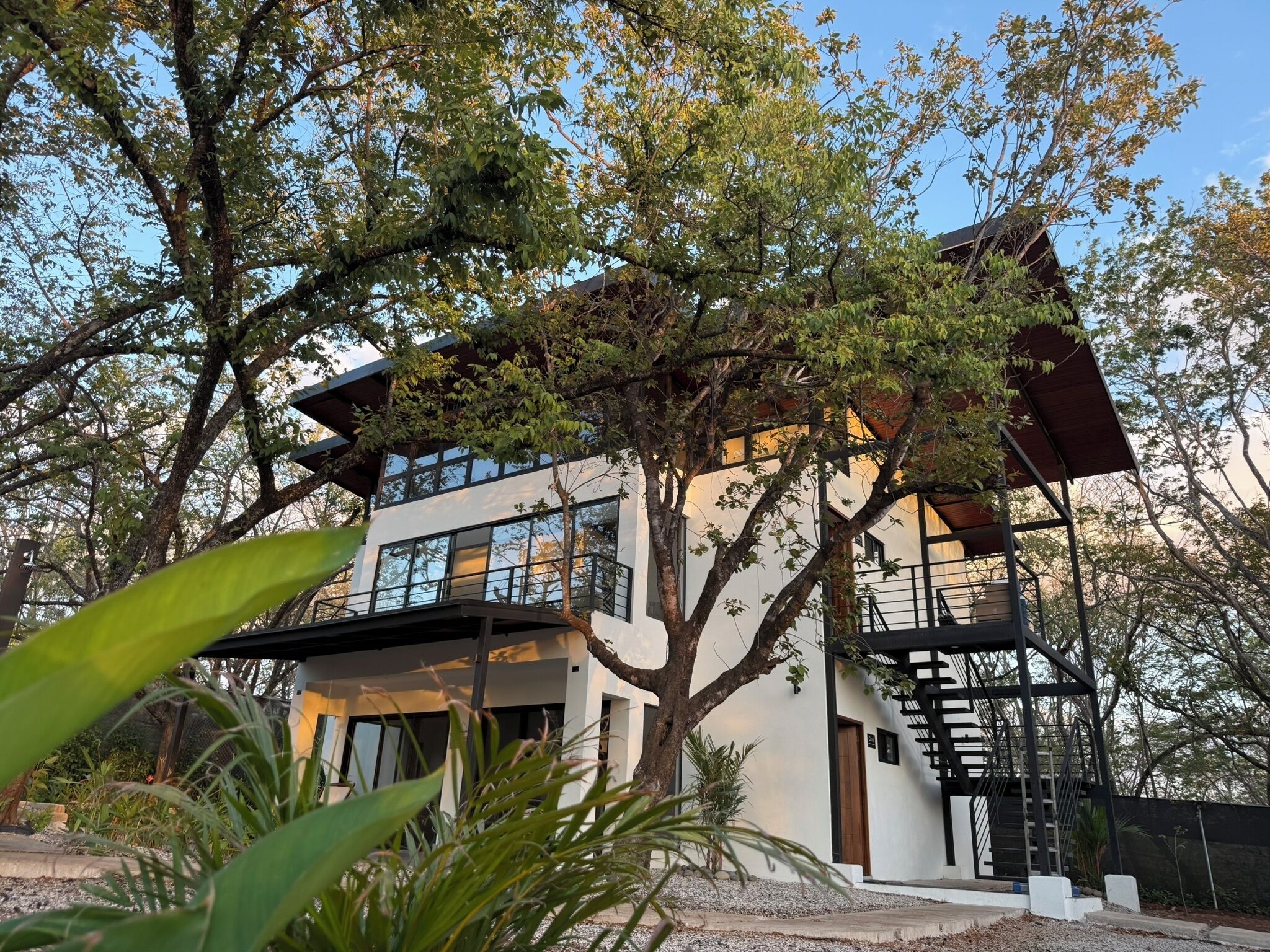 A modern two-story house with large windows, a balcony, and a staircase.