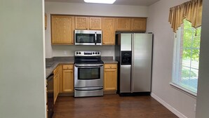 A kitchen with wooden cabinets, a stainless steel refrigerator, a microwave, and an oven. - 3-bedroom townhome in enchanting Parker - minimum 6m lease (Parker)