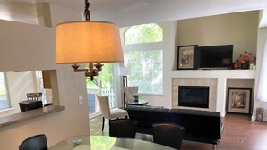 A modern living room with a glass dining table, a sofa, a fireplace, and a TV mounted above it. - 3-bedroom townhome in enchanting Parker - minimum 6m lease (Parker)