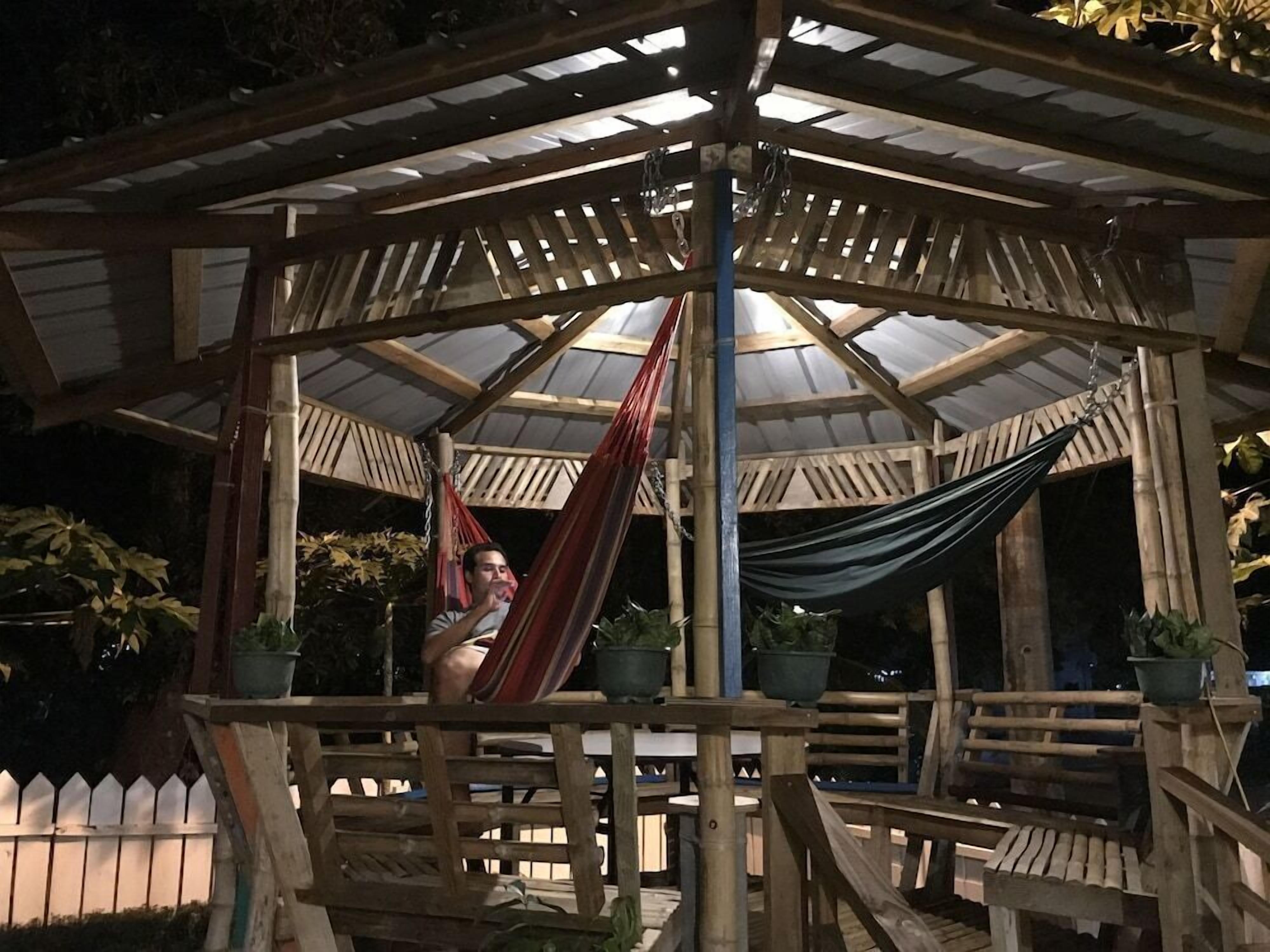 A wooden gazebo with a hexagonal roof, a hammock, and potted plants.
