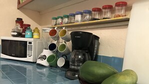 A kitchen with a microwave, coffee maker, and various containers on the counter. - The Barre (Koror)