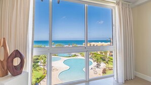 Ein Zimmer mit großem Fenster mit Blick auf Pool und Strand.