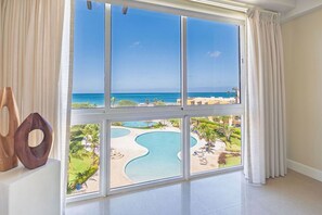 Ein Zimmer mit großem Fenster mit Blick auf Pool und Strand.