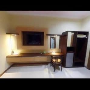 Una habitación con cama, escritorio, silla, televisor y armario.