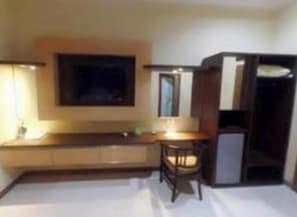 A room with a bed, a desk, a chair, a television, and a wardrobe. - Hotel Khalista (Purwakarta)
