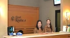 A reception desk with a wooden panel and a sign above it.