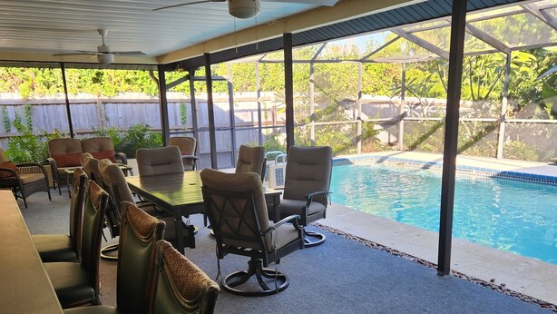 Un patio exterior con piscina, asientos techados y un ventilador de techo.