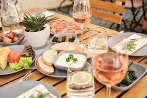 Ein Tisch ist reichhaltig mit Speisen gedeckt, darunter Brot, Oliven und ein Weinglas.