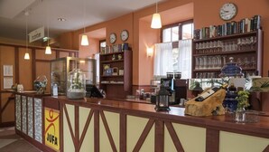 A reception area with a counter, clocks, bookshelves, and a sign reading 'JUFA'. - Jufa Meersburg am Bodensee (Meersburg)
