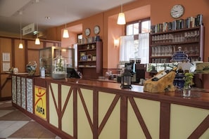 Uma área de recepç ão com balcão, relógios, estantes de livros e uma placa com a inscrição 'JUFA'.
